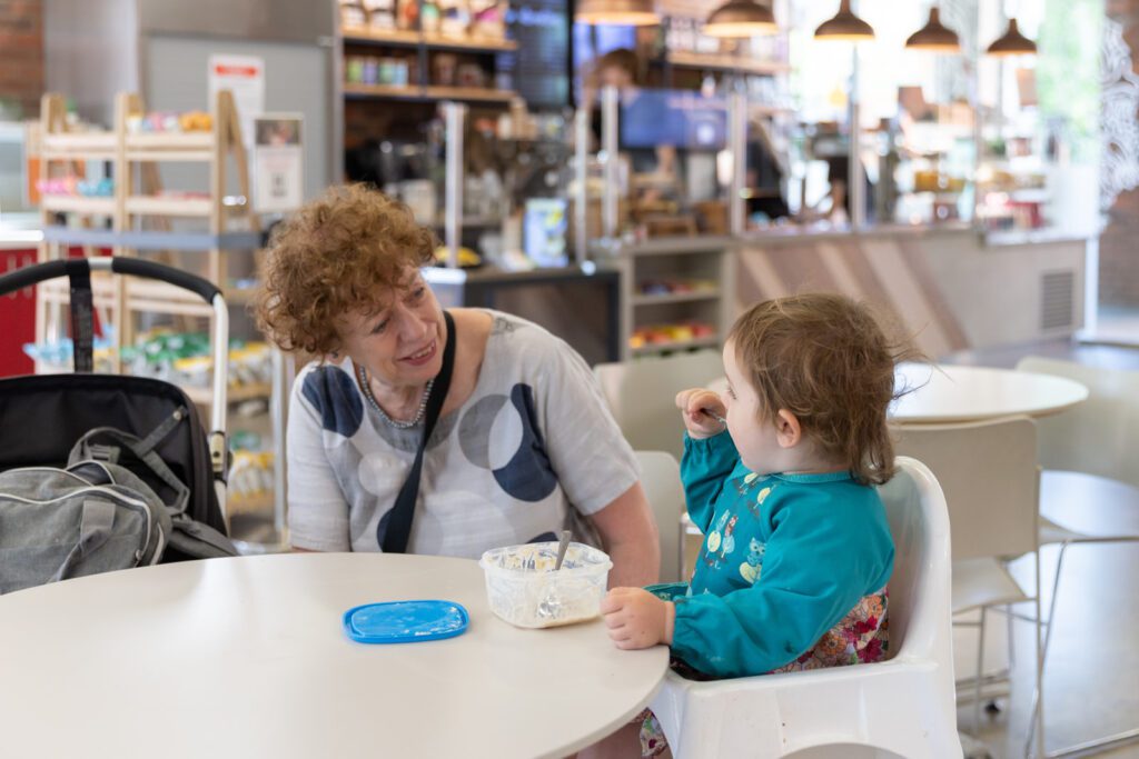 A mother and child in a high-chair at a cafe table