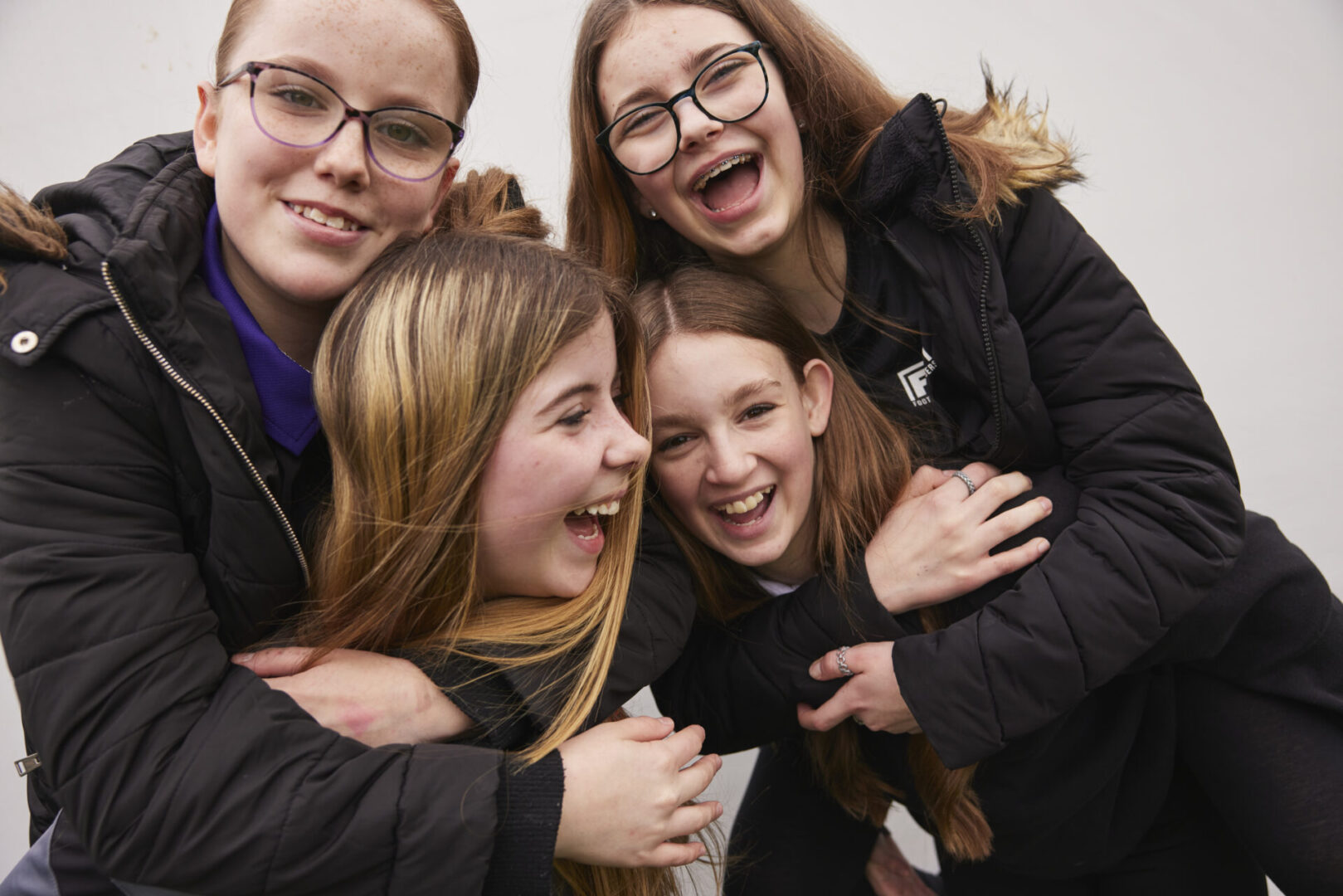 Four teen girls hugging and laughing
