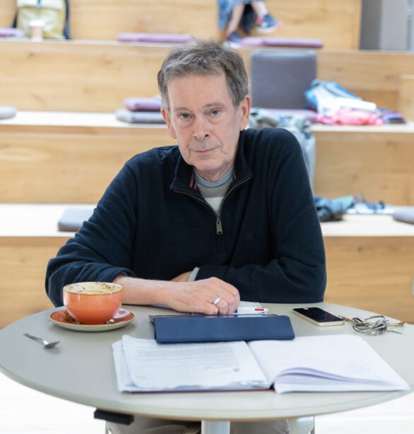 A man sitting at a cafe table, with his notebook and coffee cup