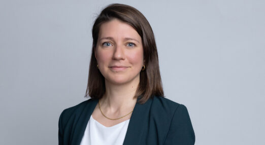 Portrait of Sarah Holloway, a woman standing in front of a plain grey background