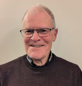 Portrait of an older man, Pat, wearing glasses and smiling