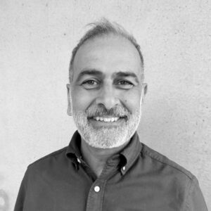 Portrait of a smiling man, with a white beard and buttoned shirt