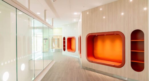 Interior of Pears Maudsley Centre, showing large orange seats, built in to the wall, with a glass wall opposite
