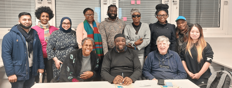 A large group of people seated and standing behind a long table