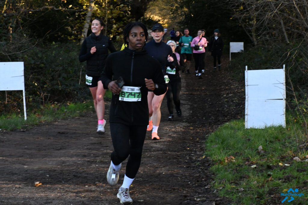 A woman running a race in a woodland setting