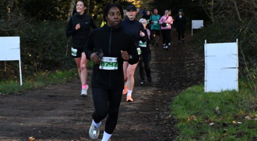 A woman running a race in a woodland setting
