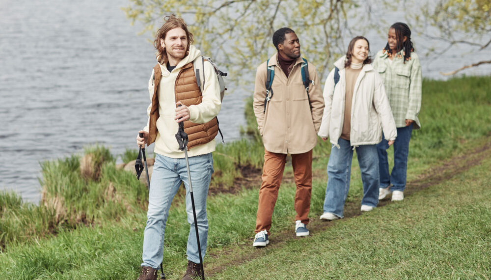 Four people walking along a path beside a lake