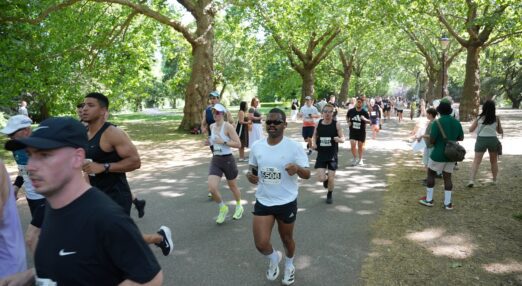 Runners during a race through a park path within tall trees